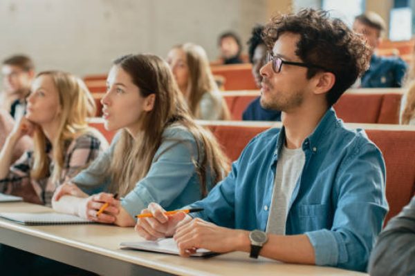 In the Classroom Multi Ethnic Students Listening to a Lecturer and Writing in Notebooks. Smart Young People Study at the College.